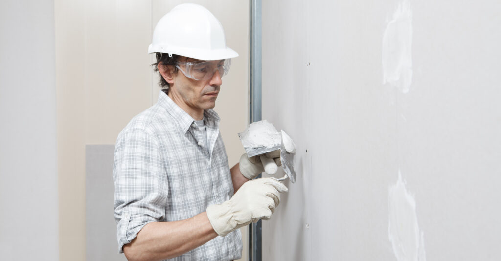 homem realizando o acabamento de uma parede branca